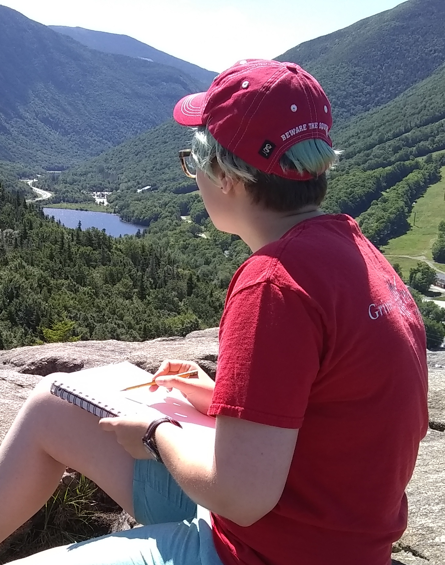 Eleanor sitting on a mountaintop sketching